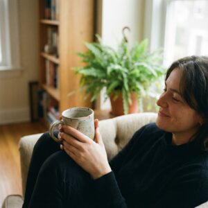 부드러운 초점의 따뜻한 배경 앞에서, 사람이 자신이 선택한 아끼는 머그잔이나 식물을 애정 어린 눈빛으로